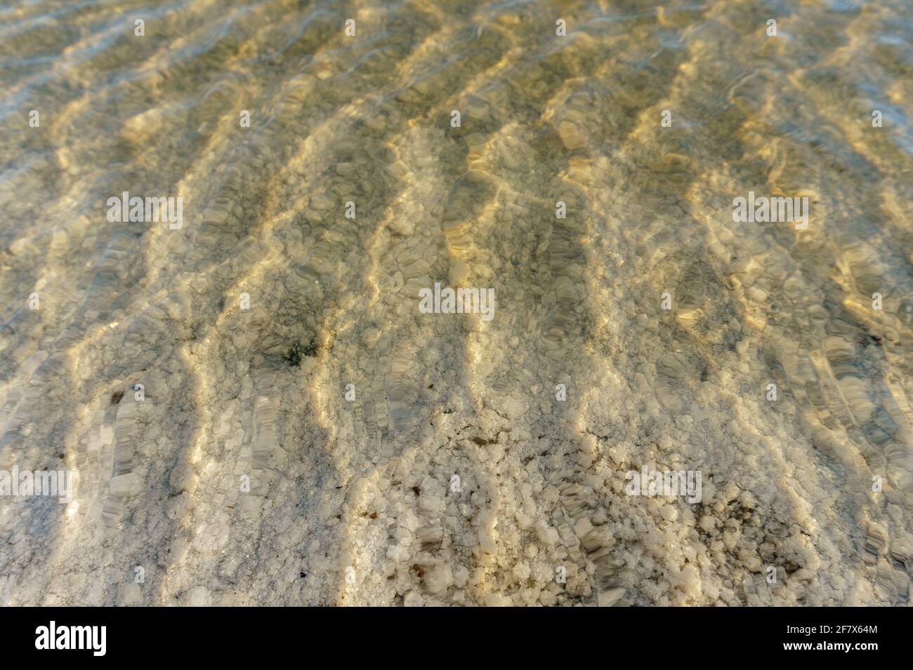 Blick auf den Grund des Salzsees Baskunchak durch klares Wasser. Salzkristalle auf dem Boden. Stockfoto