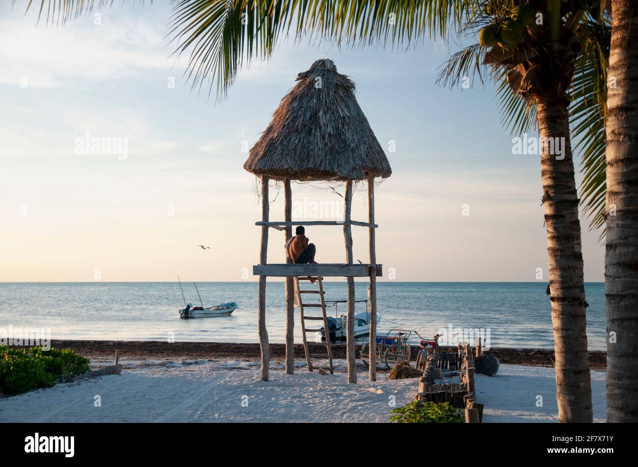 Eine hölzerne Rettungsschwimmerhütte an einem tropischen weißen Sandstrand auf Holbox Island in Mexiko. Im Hintergrund der Himmel, die Palmen und das Karibische Meer. Stockfoto
