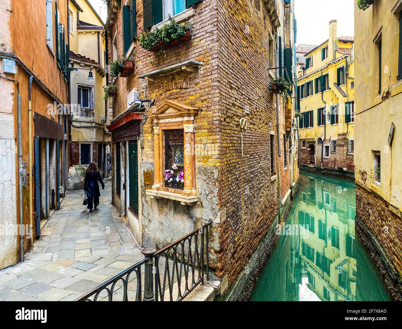 Rückansicht einer Frau, die in der Straße von Venedig spazierengeht Stockfoto