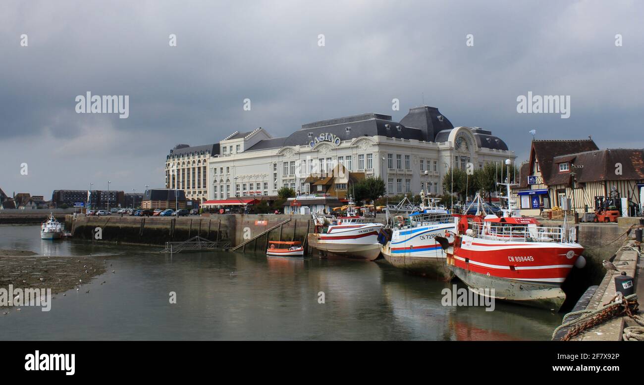Das weiße Casino an der französischen Küste in trouville mit bunten Fischerbooten im Sommer vor dem Hafen Stockfoto
