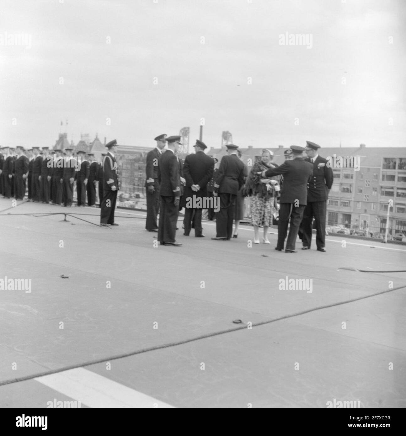 Fotoment des Staatsbesuchs des dänischen Königspaares, König Frederik IX. Und Königin Ingrid, in den Niederlanden. Die königliche Gesellschaft und ihre Courtège versammeln sich am Flugzeuglift auf dem Luftdeck von HR.Ms. Karel Doorman (1948-1968). Ist Teil der Objektserie AVDKM 540154 bis 540167. Stockfoto