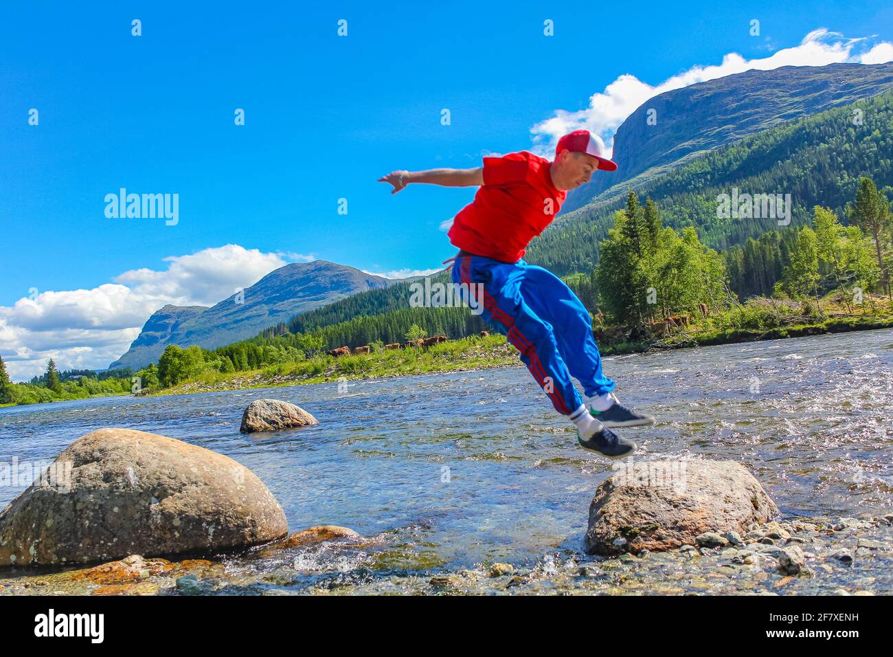 Teenager springt über einen See Hemsila mit Bergpanorama in Hemsedal Norwegen. Stockfoto