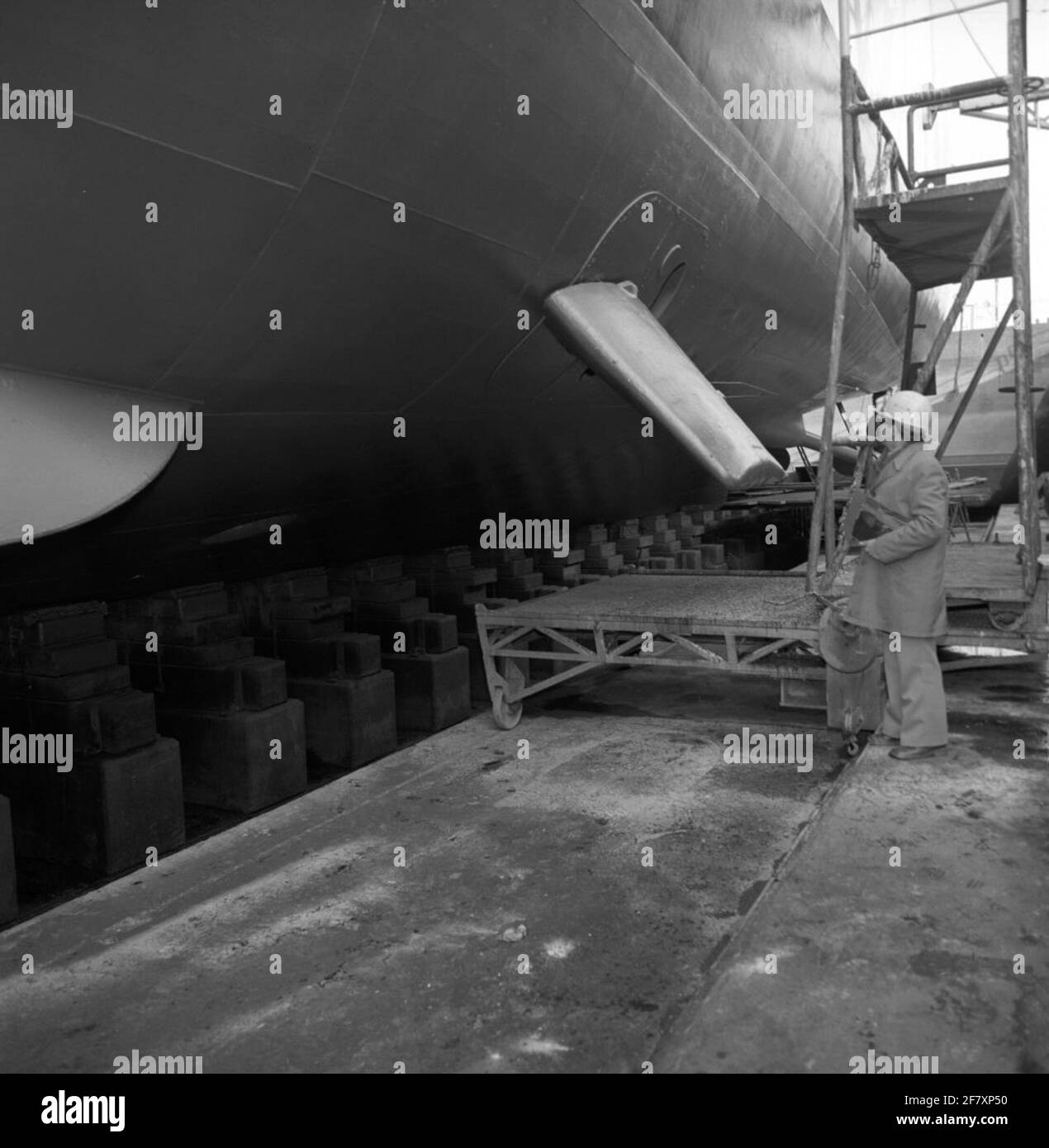 Das Unterwasserschiff der Frigate HR.Ms. Van Nes (F 805) während einer Anlegestelle während der Midlife Modernisation (MLM)-Zeit (März 1978 bis Dezember 1980) auf dem Rijkswerf (RW) in Den Helder. Eine der beiden (beweglichen) Stabilisierungsgebühren ist sichtbar. Stockfoto