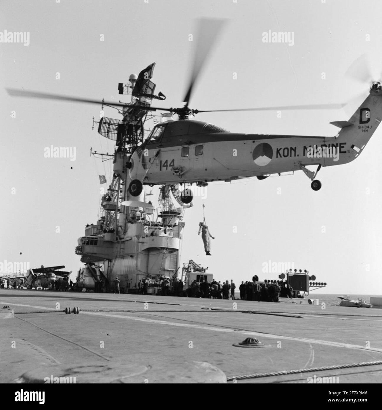 Am 19. September wird das Marijnen-Kabinett (1963-1965) mit dem Flugzeuglager hr.ms segeln. Karel Doorman (R 81) (1948-1968) (Ex-HMS Venerable 1945-1948) van den Helder nach Rotterdam. Über dem Flugdeck zeigt ein Sikorsky UH-34J Hubschrauber, der Menschen anhebet. Stockfoto
