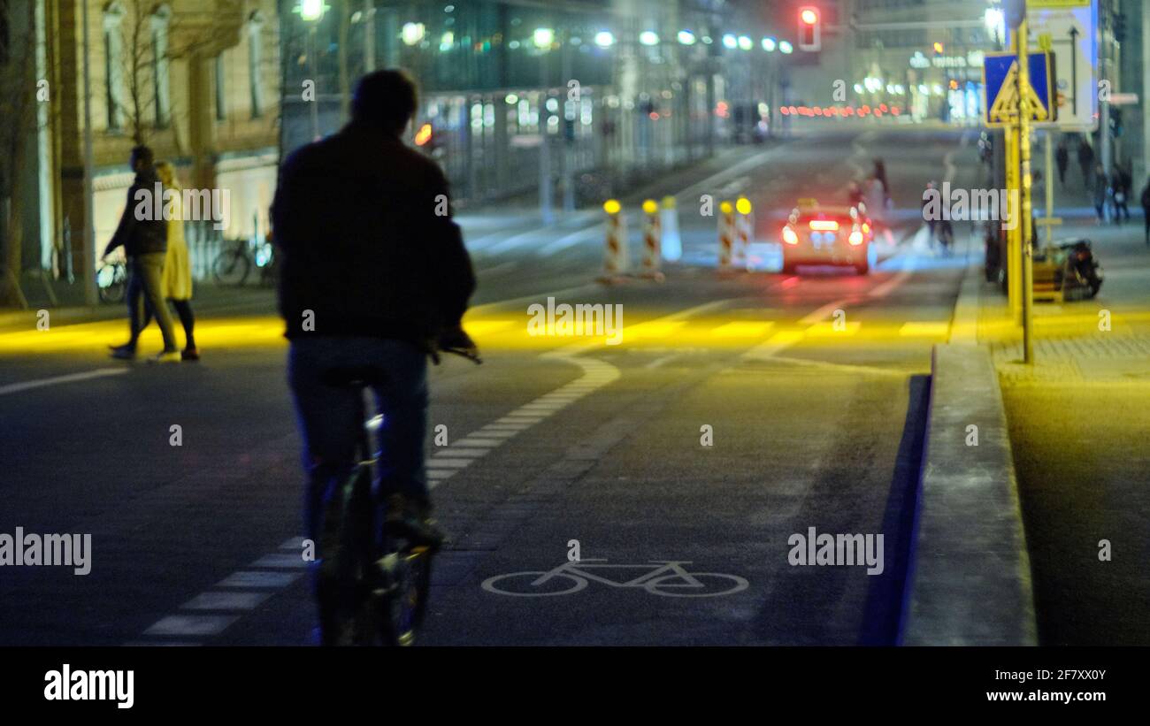 Berlin, Deutschland. März 2021. Ein Radfahrer fährt mit einem unbeleuchteten Fahrrad eine leere Wilhelm-Straße entlang auf einem Fahrradweg, der mit einem Fahrradsymbol gekennzeichnet ist. Quelle: Stefan Jaitner/dpa/Alamy Live News Stockfoto