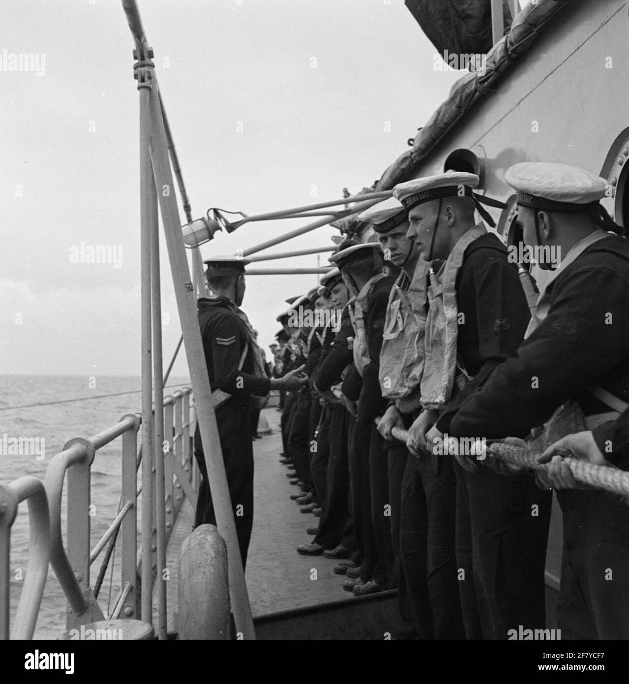 Crew-Mitglieder sind bereit, Ausgaben oder Personen entlang der Spanking-Tisch zwischen Kreuzer HR.Ms. Die sieben Provinzen (C 802, Flaggschiff von Smaldeel 5) und U-Boot-Jäger HR.Ms. Transfer Friesland (D 812), Juni 1957. Stockfoto