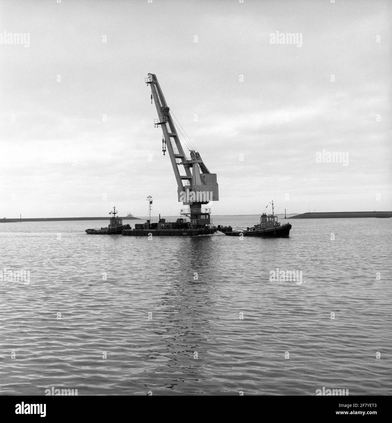 Die neue (treibende) Armatur (Y 8514) des Rijkswerf (RW) in Den Helder wird im Februar 1975 von Marinesleepoot Dombo (Y 8017, vorne) und Bambi (Y 8016, hinten) an seinen Arbeitsplatz geklungen. Stockfoto