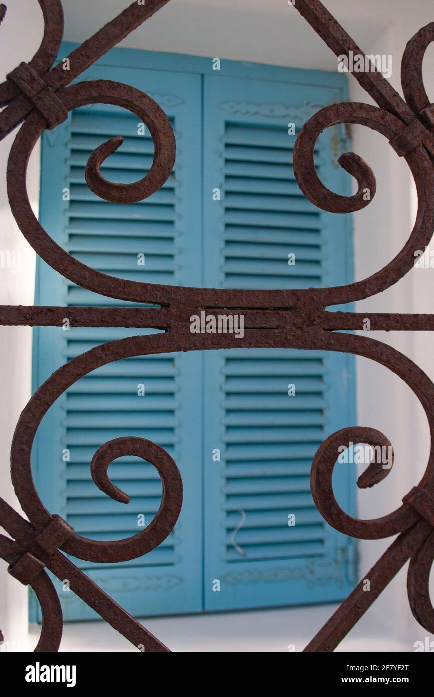 Beispiel einer dekorativen Schmiedeeisenarbeit, die bereits von der Zeit verrostet wurde, in einem Fenster eines Hauses in Mykonos Stadt, Kykladen ist Stockfoto