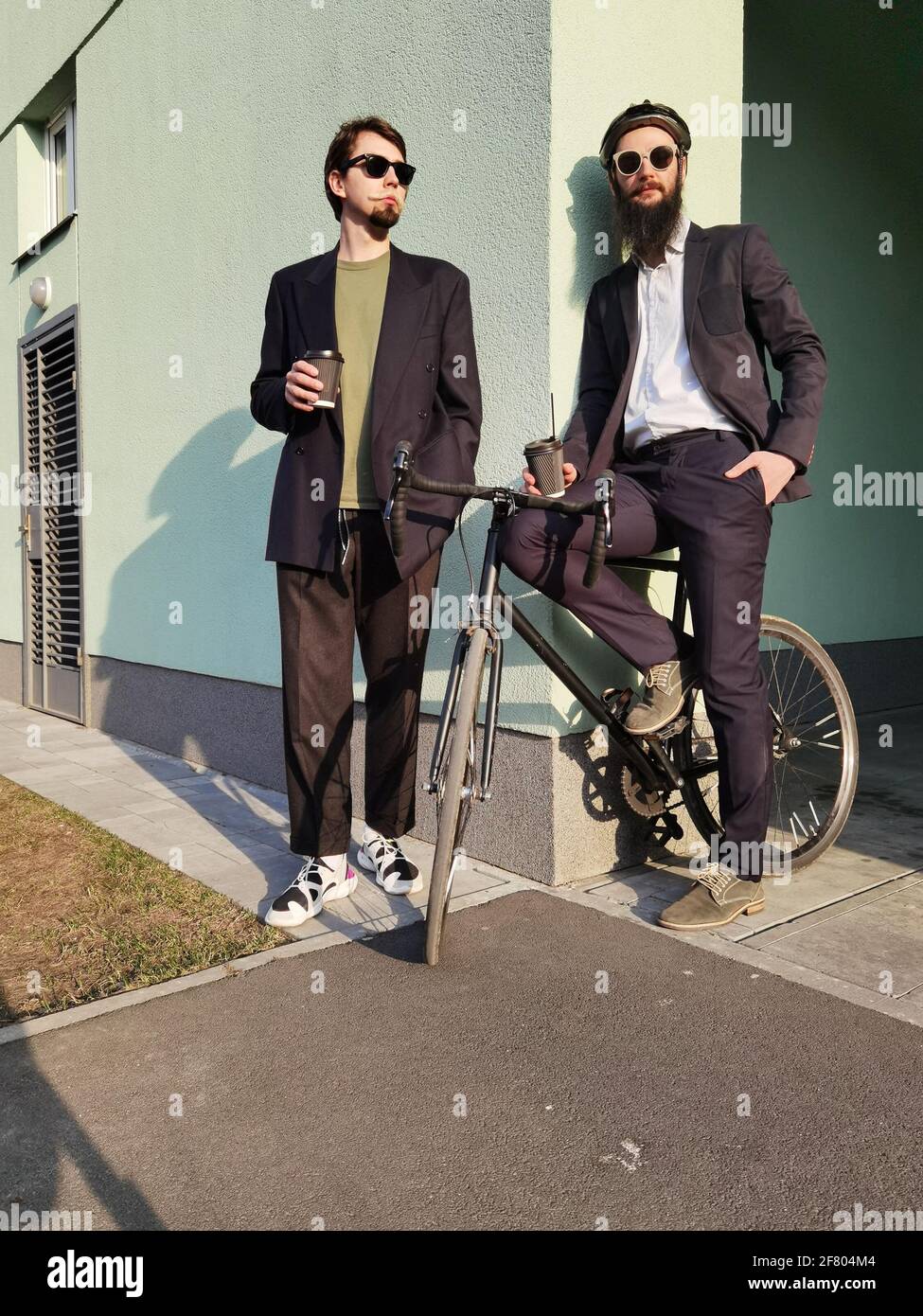 Zwei junge Freundinnen, die lässig angezogen waren, verbrachten Zeit zusammen in der Stadt und tranken beim nächsten Fahrrad Kaffee zum Mitnehmen. Stockfoto