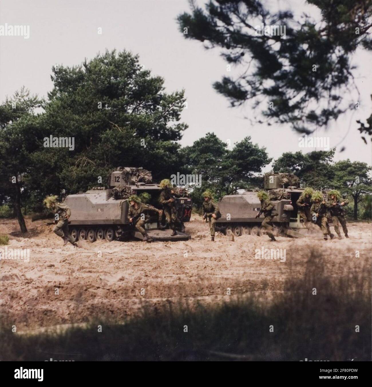 Soldaten verlassen schnell ein YPR 765 PRI (Panzerung Raupeninfanterie-Fahrzeug) über die abgesenkte Heckklappe, um den Kampf zu Fuß zu führen. Das Fahrzeug ist mit einer 25mm-Schnellfeuerwaffe von Oerlikon bewaffnet. Stockfoto