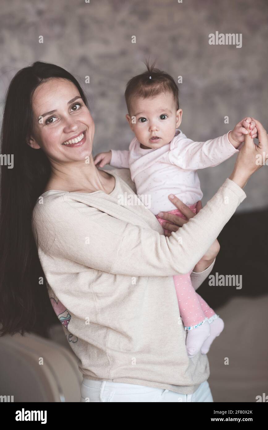 Mutter hält Baby Mädchen zu Hause. Neugeborenes Kind auf weiblichen Händen im Haus. Mutterschaft. Mutterschaft. Stockfoto