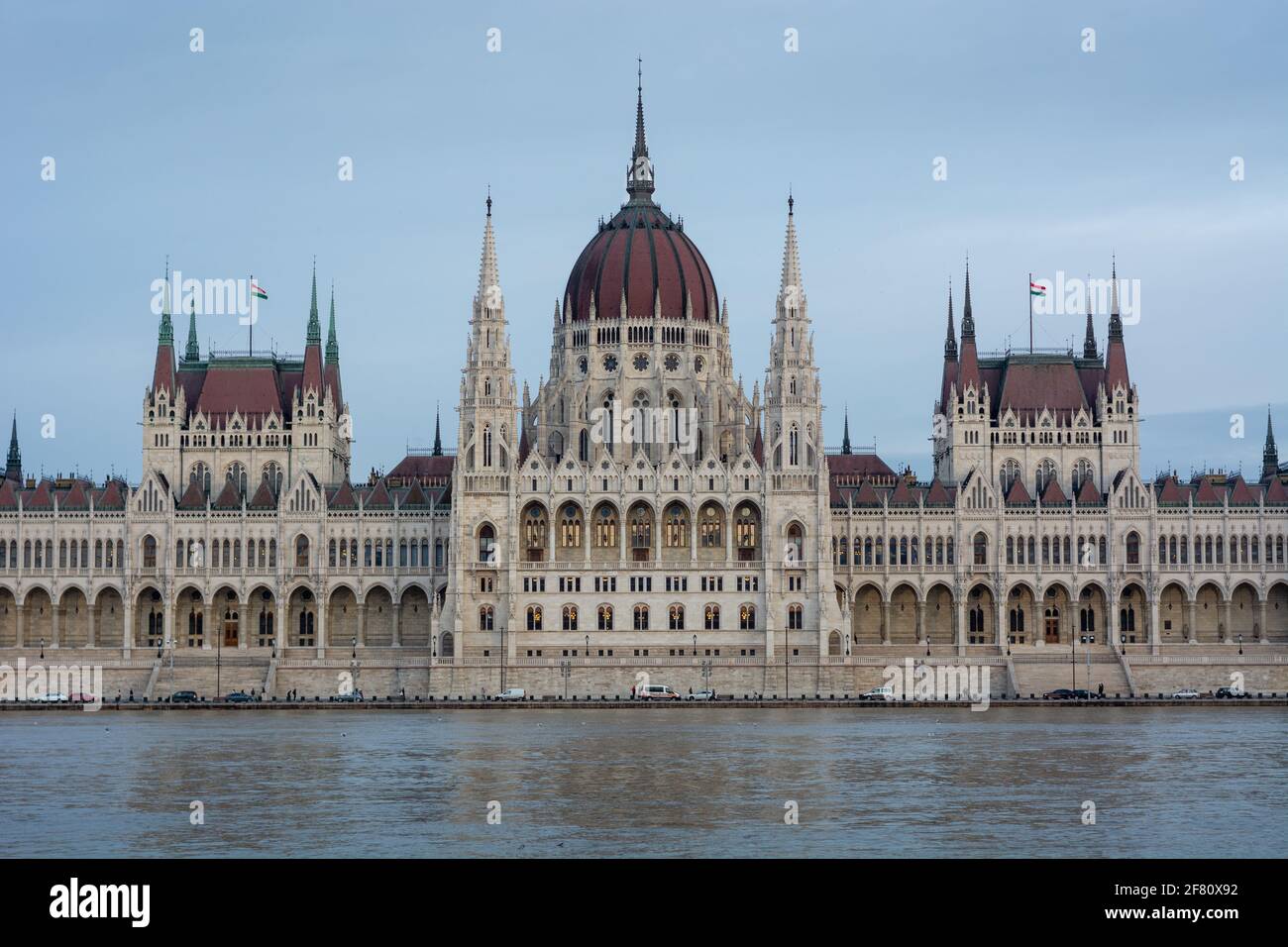 Die Front des ungarischen parlaments in sanftblauem Sonnenuntergang Licht mit dem Haupteingang in der Stadt Budapest mit Donau im Vordergrund bewölkt Stockfoto