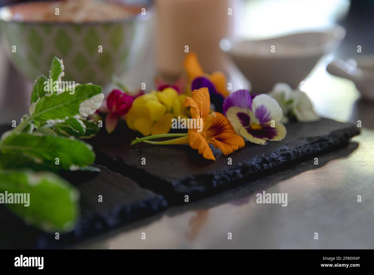 Schiefer mit frischen essbaren Blumen mit verschwommenem Hintergrund Stockfoto