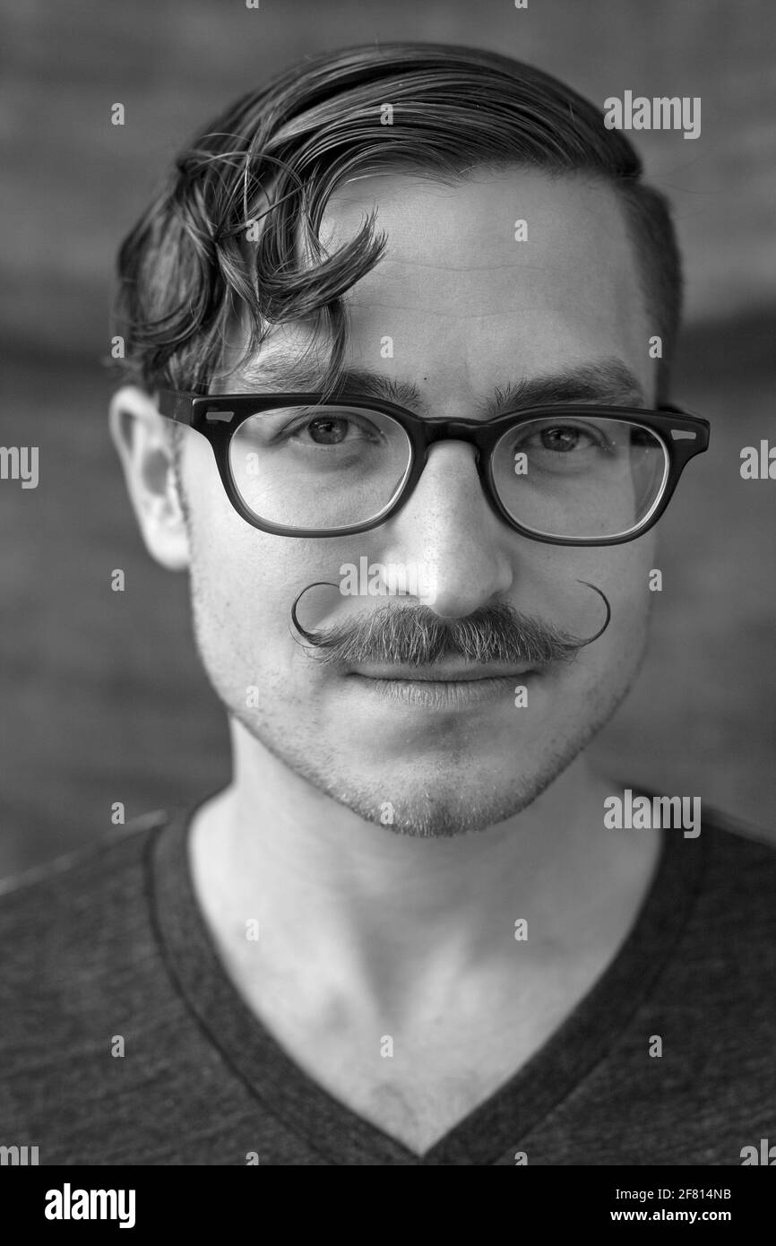 Junger Mann mit Schnurrbart und Brille Stockfoto