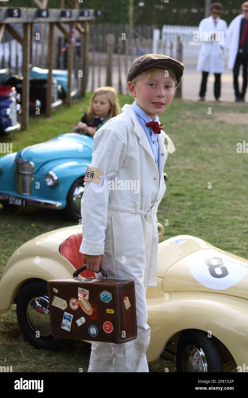 Kleiner Junge mit Koffer vor Pedalautos beim Goodwood Revival Meeting in Chichester, West Sussex UK. Stockfoto