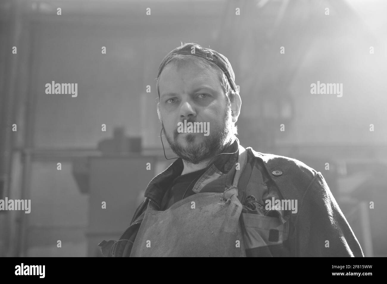 Ein Arbeiter mit einem Bart in Overalls in einem Produktionsraum in einer Fabrik. Nahaufnahme. Stockfoto