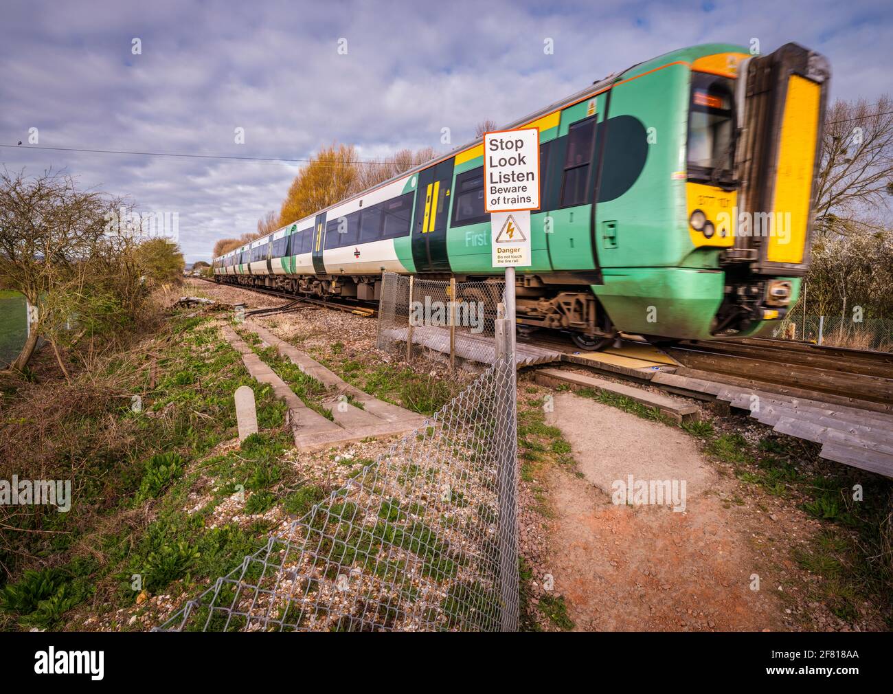 Ein Zug fährt über einen öffentlichen Fuß und überquert eine Bahnlinie in Pevensey in der Nähe von Eastbourne, East Sussex, Großbritannien. Stockfoto