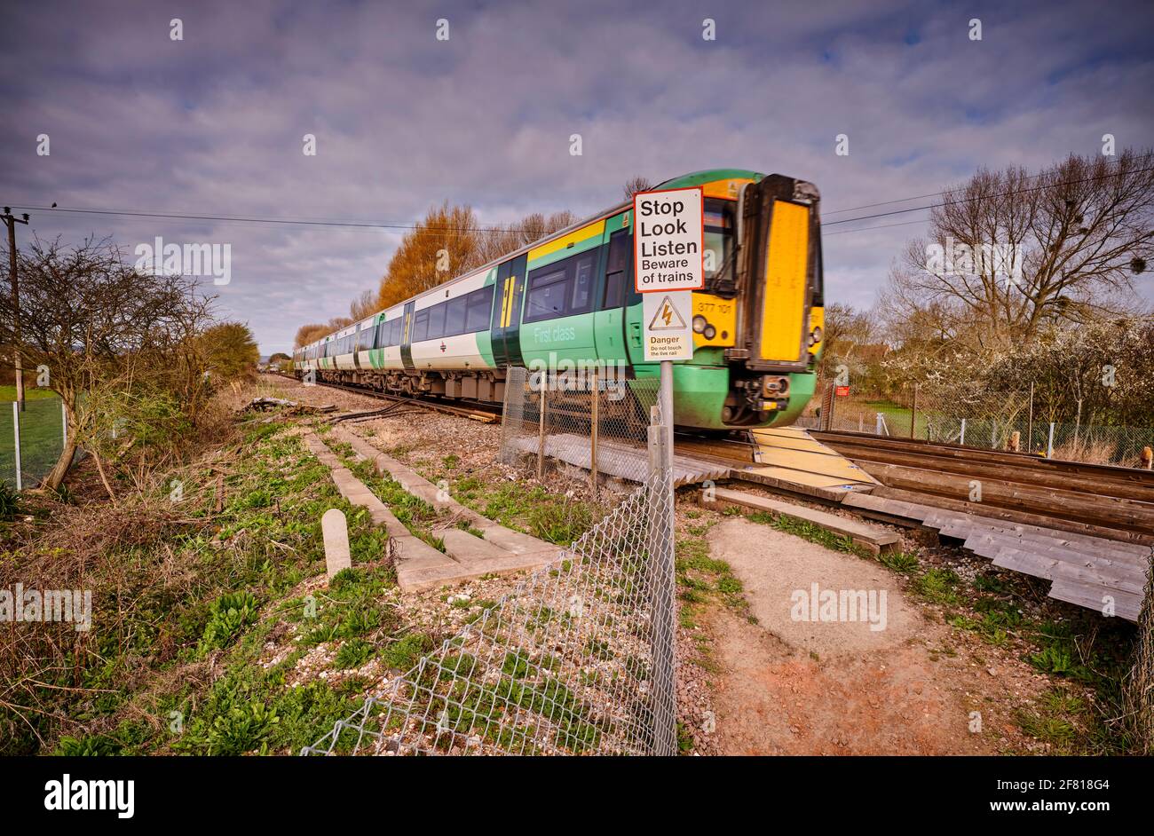 Ein Zug fährt über einen öffentlichen Fuß und überquert eine Bahnlinie in Pevensey in der Nähe von Eastbourne, East Sussex, Großbritannien. Stockfoto