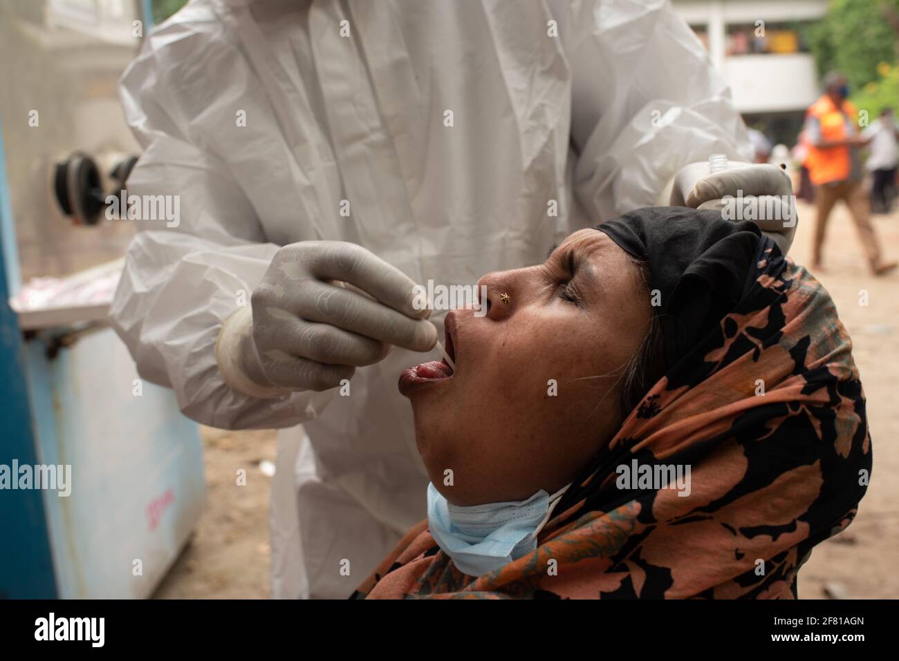 Dhaka, Bangladesch. April 2021. Eine Frau reagiert, als eine medizinische Mitarbeiterin, die persönliche Schutzausrüstung trägt, einen Tupfer von ihr nimmt, um in einem Krankenhaus in Dhaka auf eine Coronavirus-Krankheit (COVID-19) zu testen. Quelle: Fatima-Tuj Johora/ZUMA Wire/Alamy Live News Stockfoto