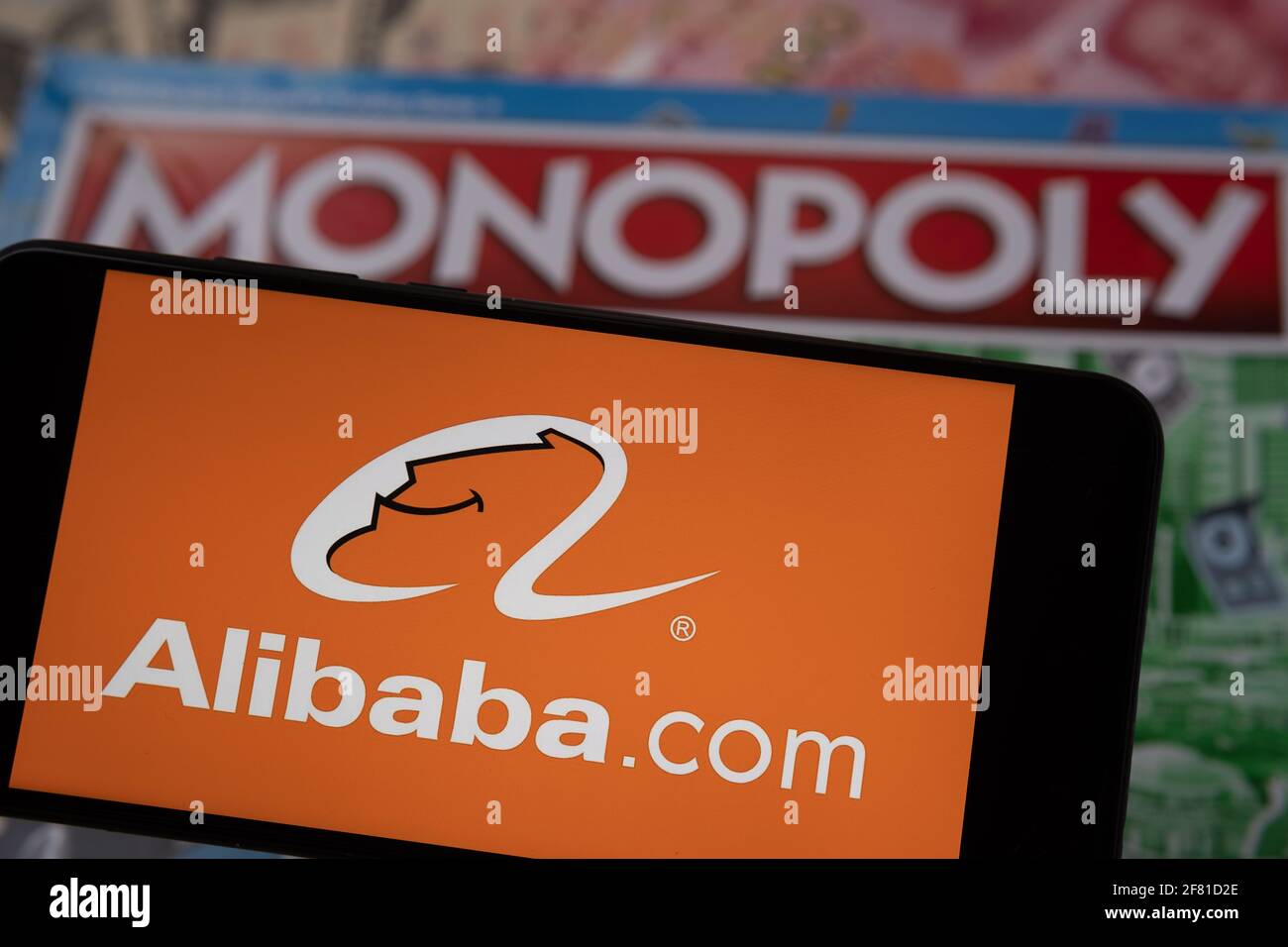 Alibaba-Logo auf dem Smartphone, das auf Monopoly Spiel platziert wird gesehen. Selektiver Fokus. Unscharfer Hintergrund. Konzept. Staffrod, Großbritannien, 10. April 20 Stockfoto