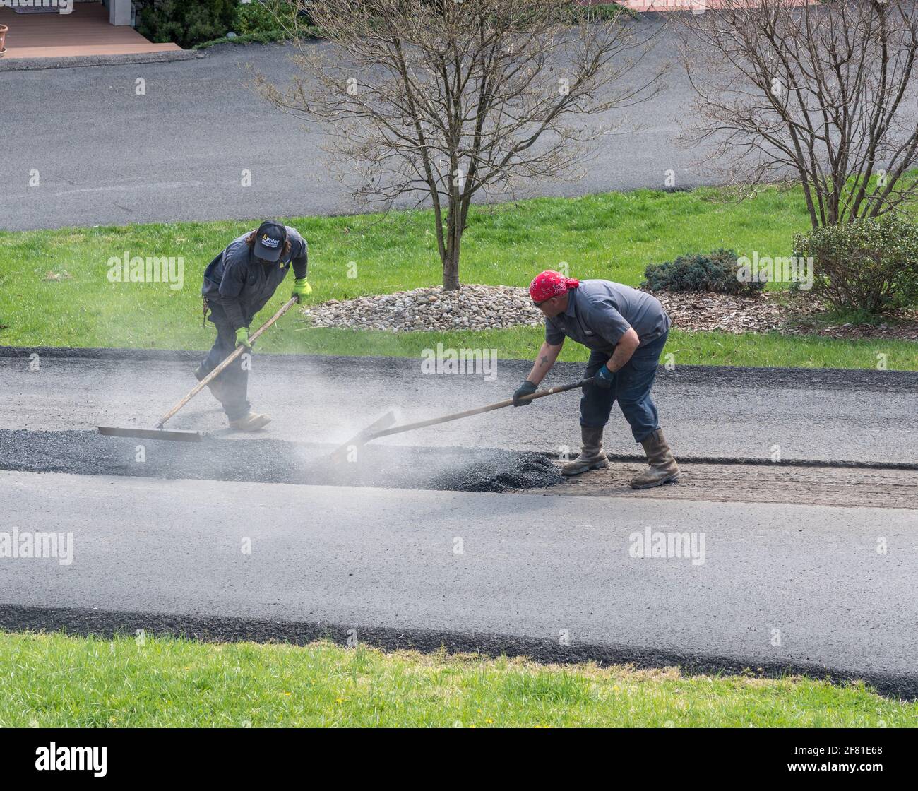 Morgantown, WV - 7. April 2021: Arbeiter, die eine Schicht Asphalt oder extra Blacktop auftragen, um Schäden an der Asphaltstraße zu reparieren Stockfoto