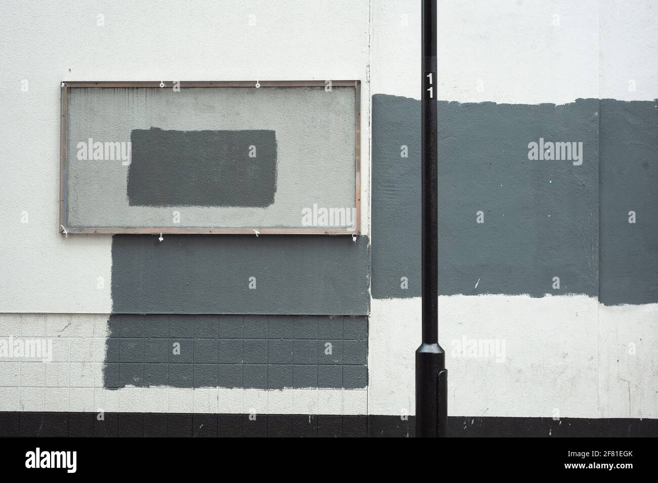 Vertuschende graue Farbe an weißer Wand und leerem Rahmen. Einzigartige Straßenfassade im Mark Rothko-Stil. Urbaner abstrakter Hintergrund mit Kopierraum. London, Großbritannien Stockfoto
