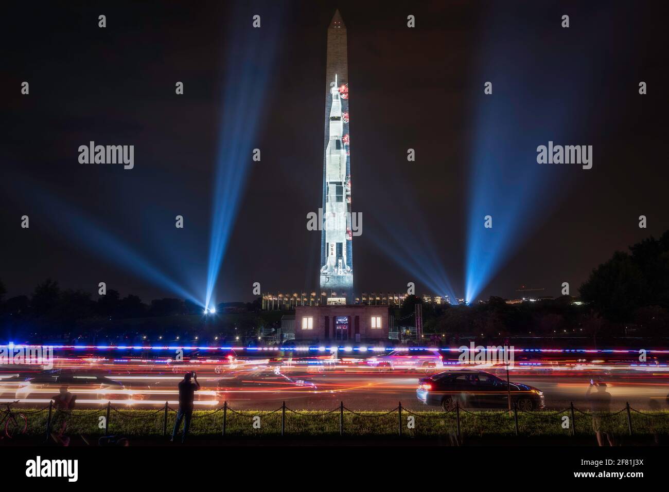 Vor dem Washington Monument rasten Polizeilichter über die 15th Street, während die „Go for the Moon“, die Saturn V Rakete, angezeigt wird. Stockfoto