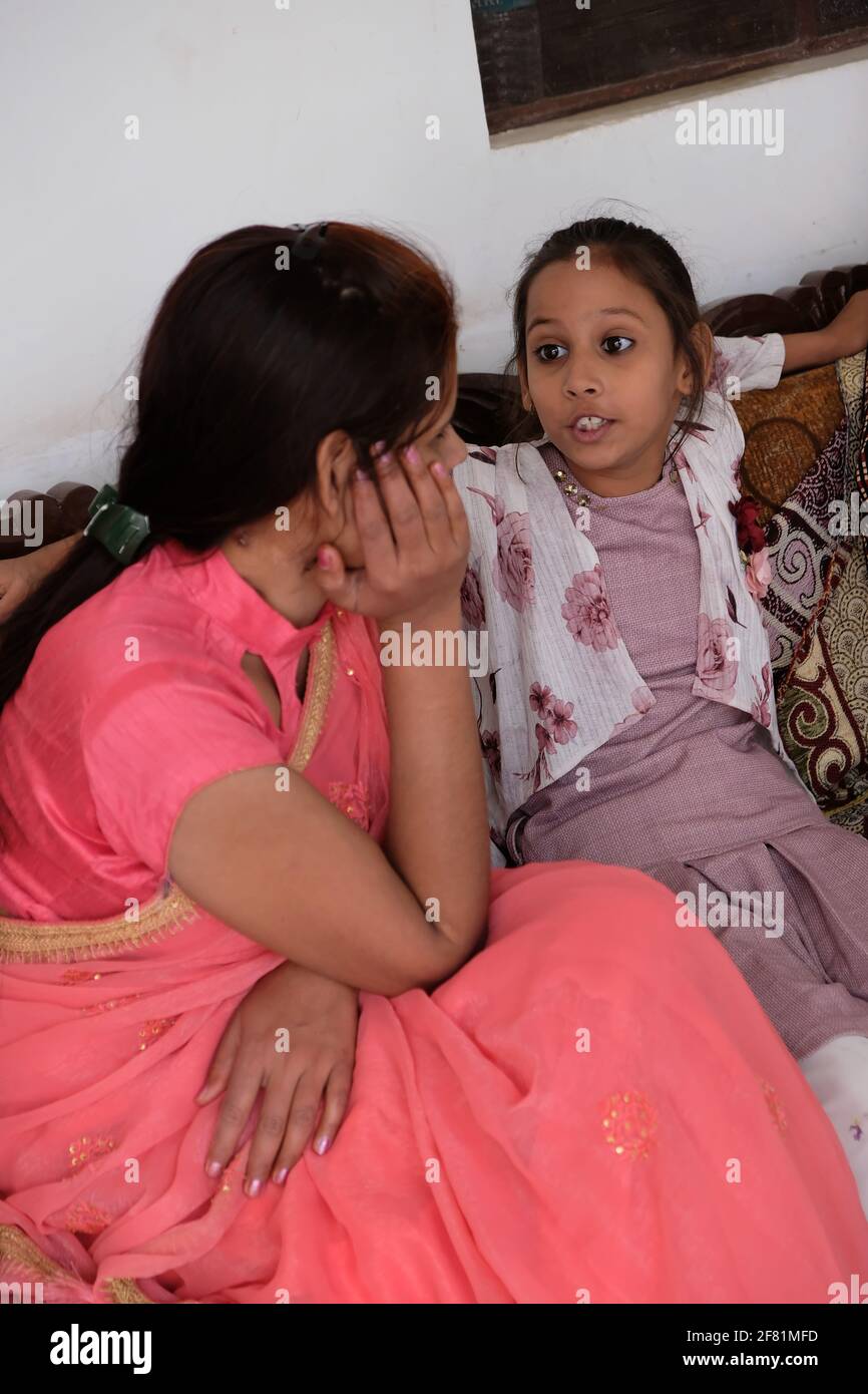 Eine Nahaufnahme einer Inderin, die mit ihr spricht Tochter, während sie auf einer Couch sitzt Stockfoto