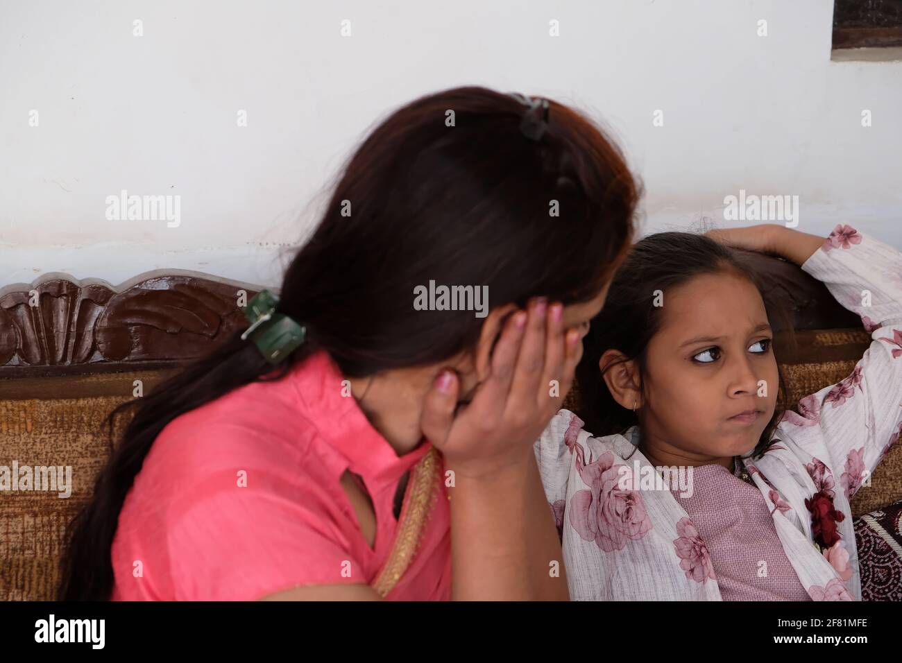 Eine Nahaufnahme einer Inderin, die mit ihr spricht Tochter, während sie auf einer Couch sitzt Stockfoto