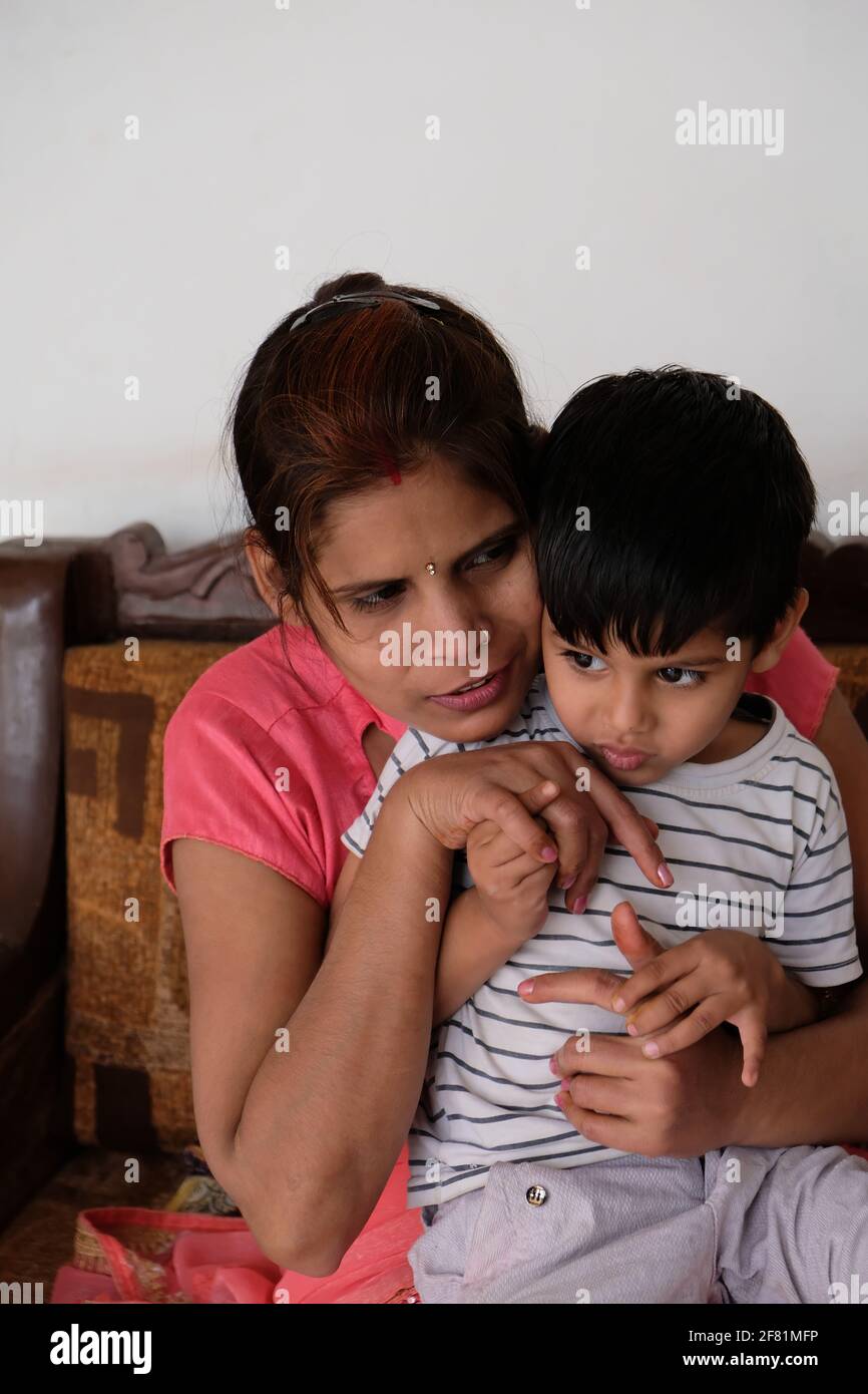 Ein flacher Fokus eines indischen Jungen, der umarmt wird Ihre Mutter zeigt mütterliche Liebe Stockfoto