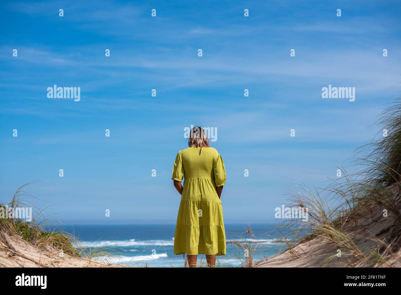 Frau, die auf einer Klippe steht und das Meer beobachtet Stockfoto