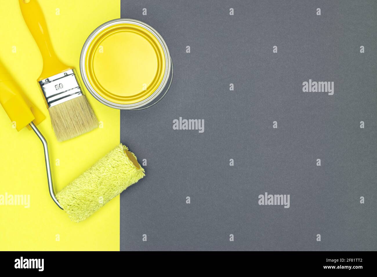 Malwerkzeuge für Hausrenovierung - Pinsel, Farbrolle und Dose mit gelber Farbe. Draufsicht. Stockfoto