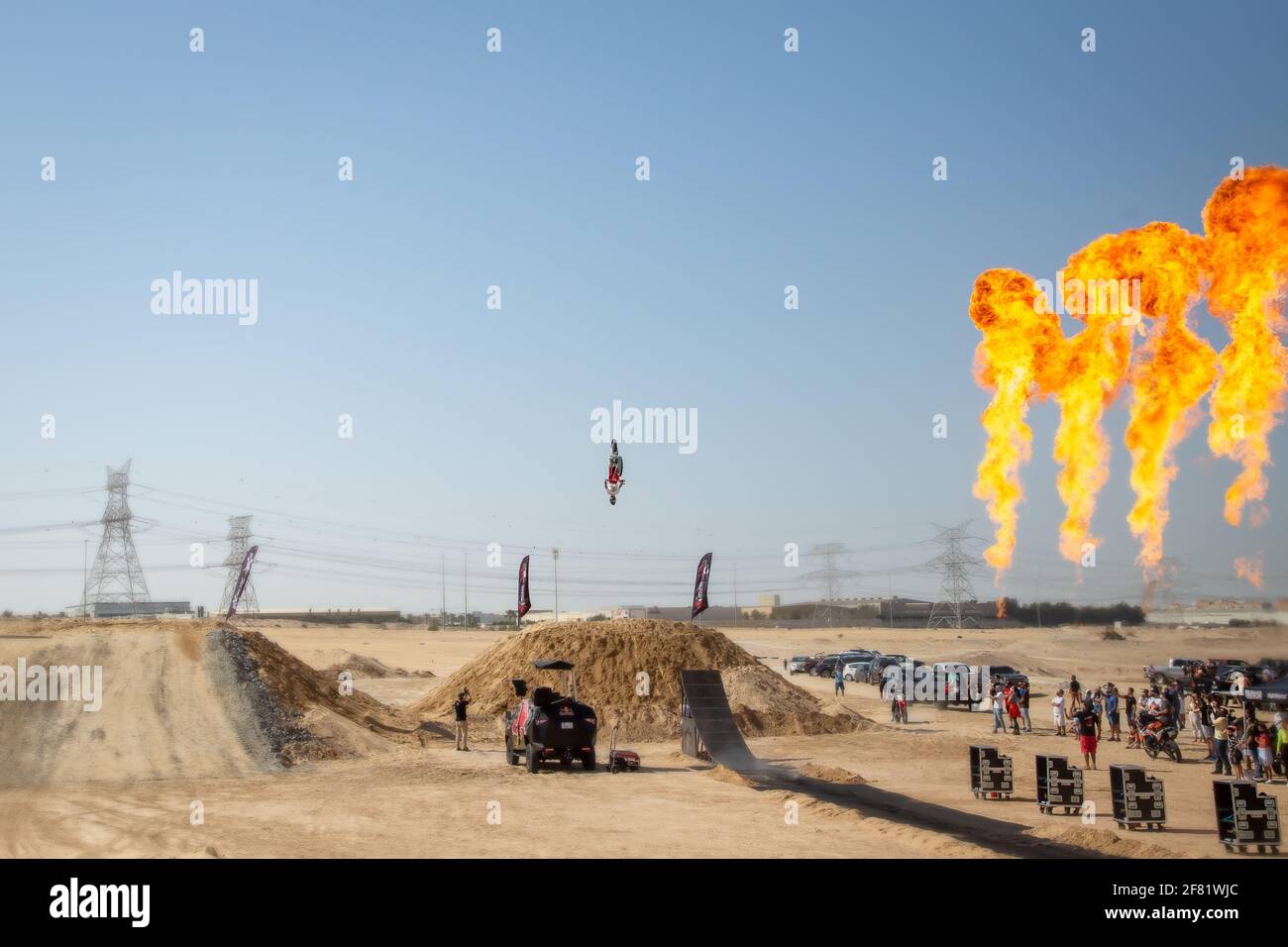 DUBAI, VEREINIGTE ARABISCHE EMIRATE - 31. Jan 2021: motocross-Freestyle-Fahrer und Motorräder springen in der Wüste mit Dünen und Flammen Stockfoto