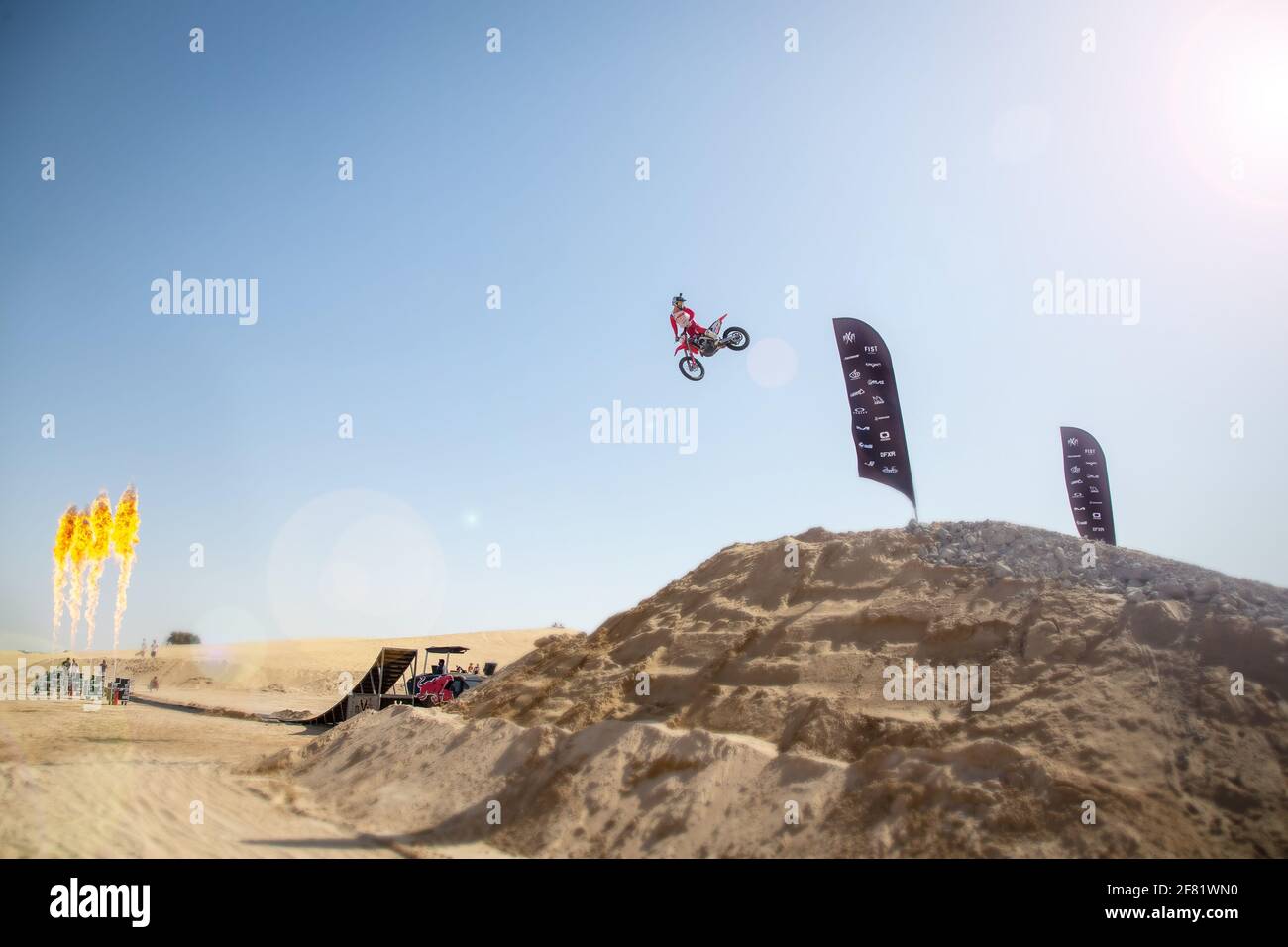 DUBAI, VEREINIGTE ARABISCHE EMIRATE - 31. Jan 2021: motocross-Freestyle-Fahrer und Motorräder springen in der Wüste mit Dünen und Flammen Stockfoto