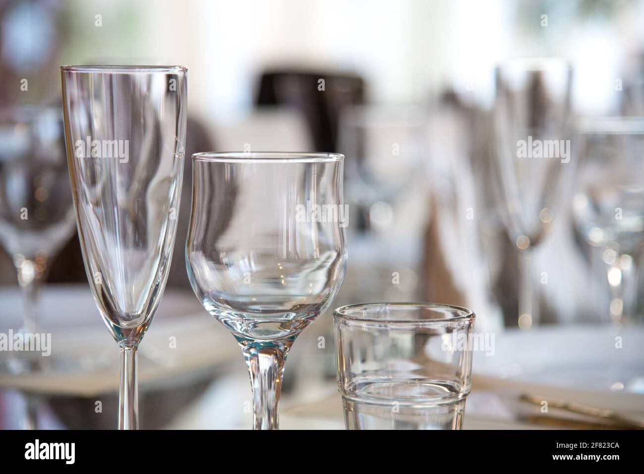 Im Restaurant wird ein Tisch mit Gläsern für Wein, Champagner und Cognac, Servietten und weißen Tellern für die Gäste serviert Stockfoto