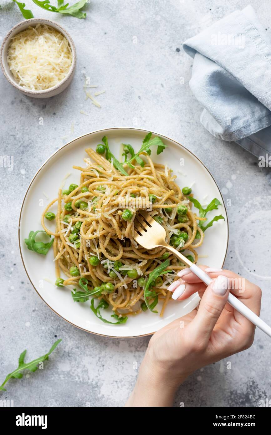 Frau, die Pasta-Spaghetti mit grünen Erbsen und Avocado isst Stockfoto