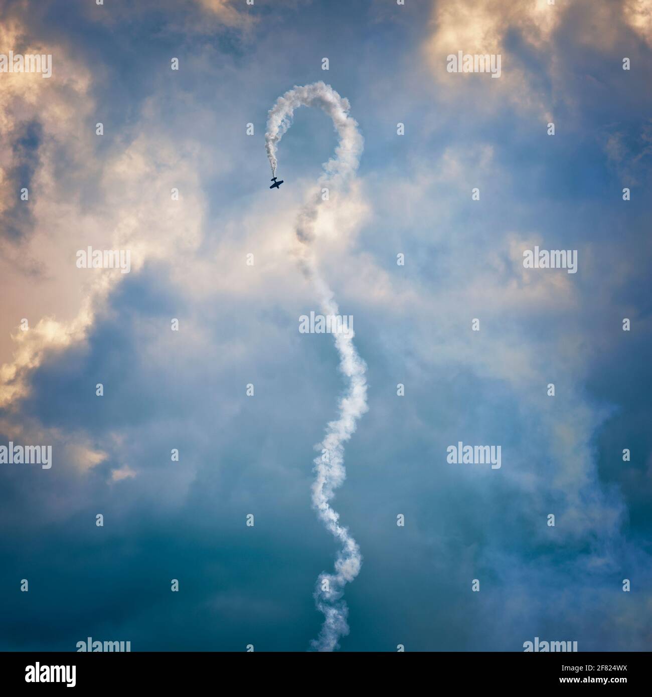 Airshow Mit Luftbildanzeige. Ein Flugzeug, das Luftkunstflug mit einer Rauchspur vor einer launischen Himmelskulisse durchführt. Stockfoto