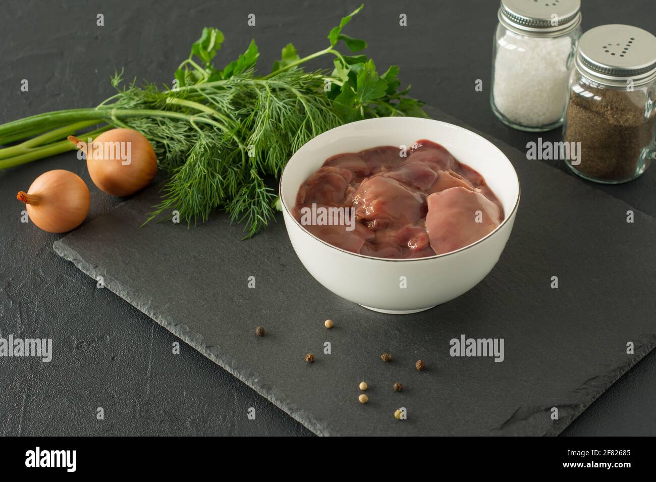 Rohe Hühnerleber in Schüssel auf schwarzem Hintergrund. Zutaten zum Kochen. Stockfoto