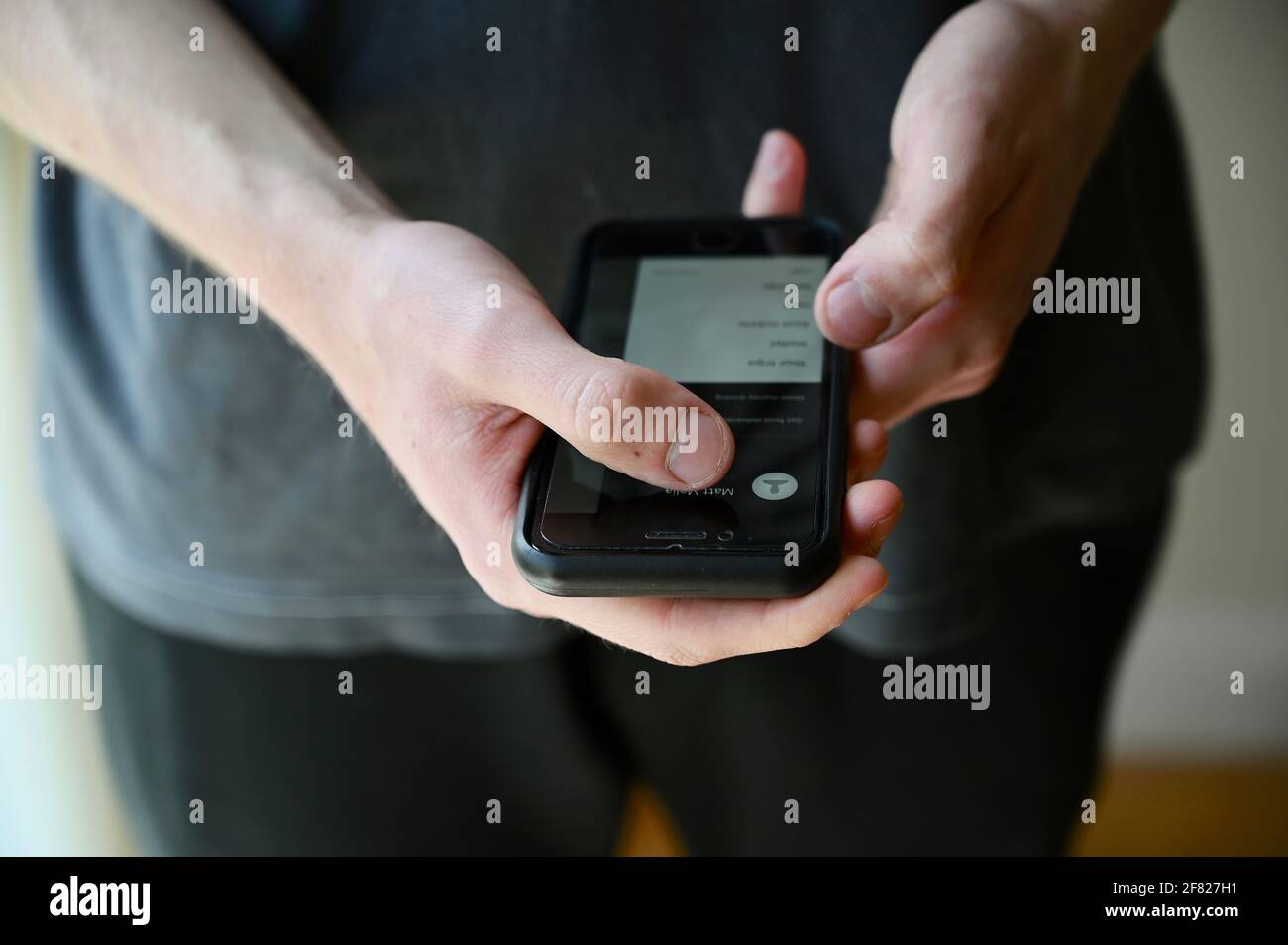 Nahaufnahme eines jungen Mannes, der auf seinem Mobiltelefon auf die Uber-App zugreift. Stockfoto