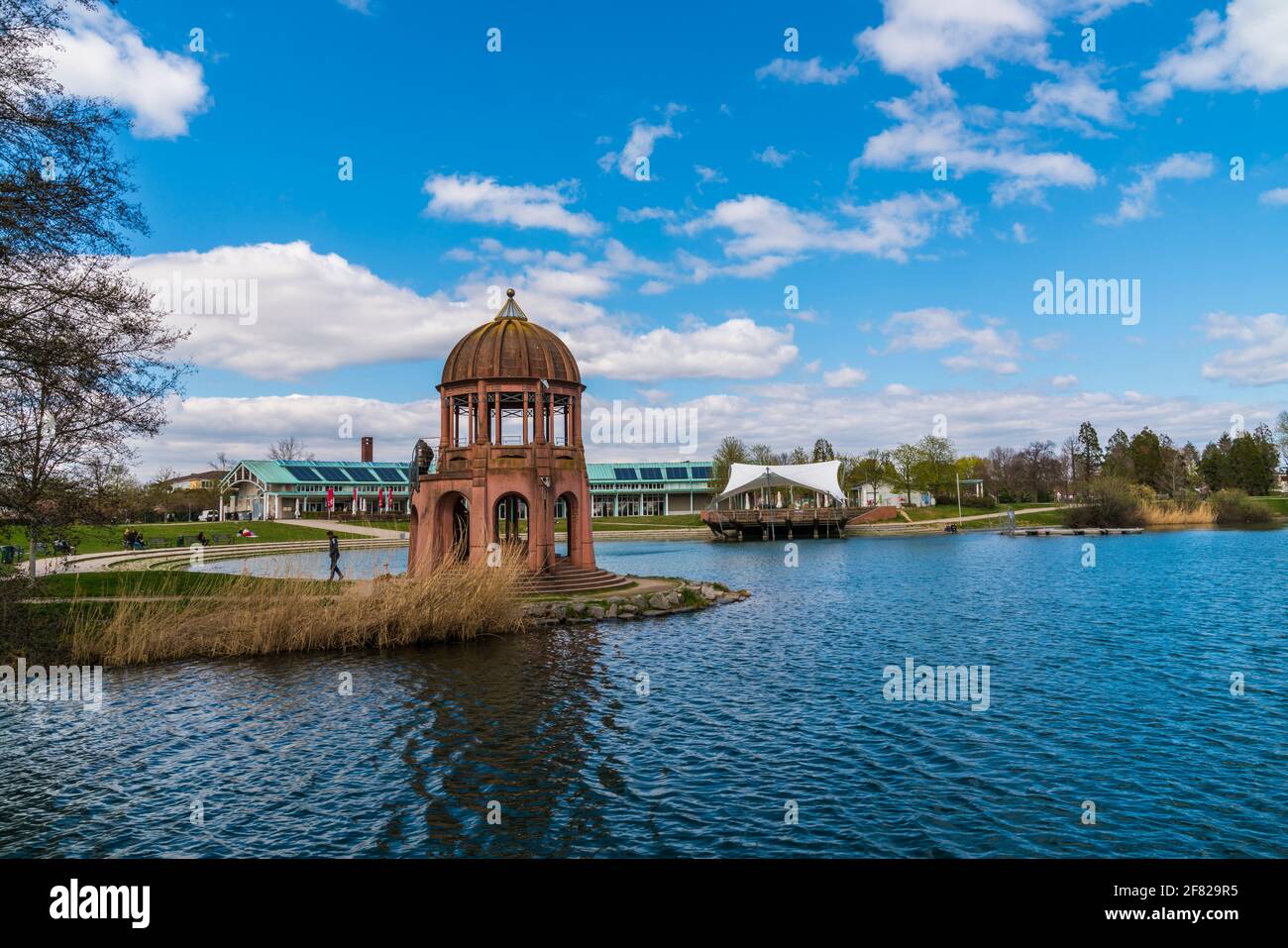 Freiburg im Breisgau, Deutschland, 3. April 2021, Menschen, die am sonnigen Tag im Frühjahr im Stadtpark um das seepark-Wasser wandern Stockfoto