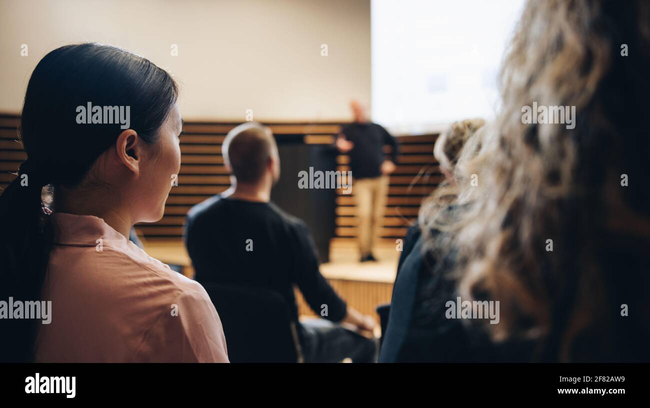 Rückansicht eines Publikums, das an einer Firmenveranstaltung teilnimmt. Weibliche professionelle sitzen in einem Seminar und hören die Rede. Stockfoto