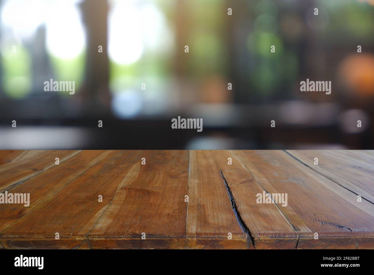 Leerer Holztisch vor dem abstrakten Blurred Cafe, Restaurant in der Nacht. Für die Montage der Produktanzeige oder für das Design eines visuellen Layouts - Bild Stockfoto