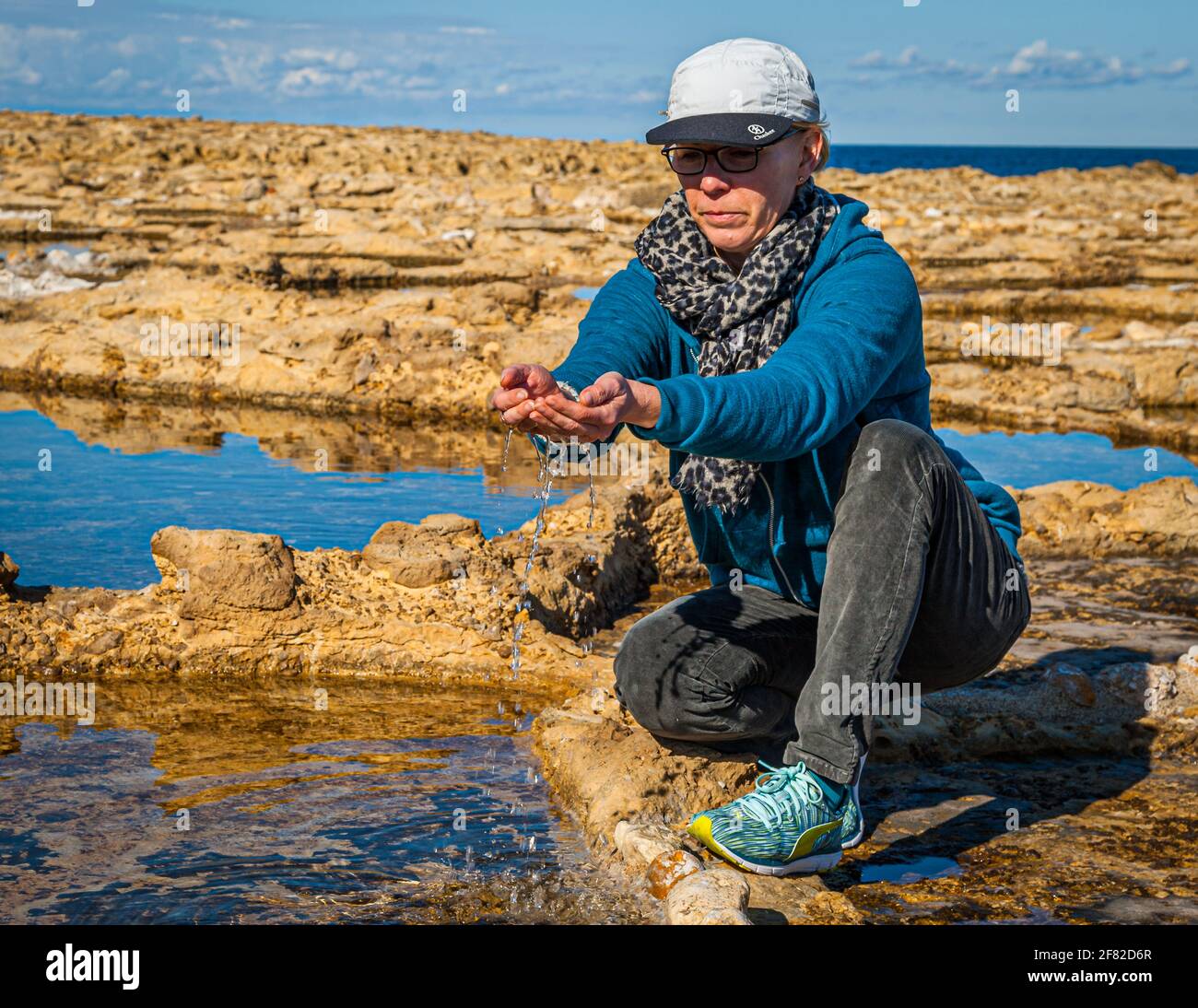 Die Lebensmitteljournalistin Angela Berg schöpft das salzige Wasser von an Uralte Salzpfanne Stockfoto