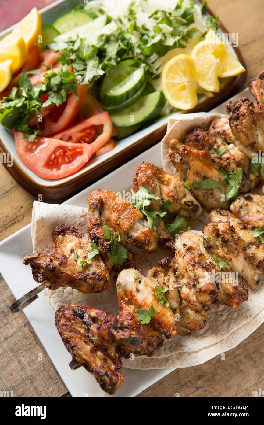 Britische Hähnchenflügel, die in Ras el Hanout marokkanischen Gewürzen mariniert wurden, bevor sie zu Hause Spieße und gegrillt wurden. Serviert mit einem Koriander, auf Stockfoto