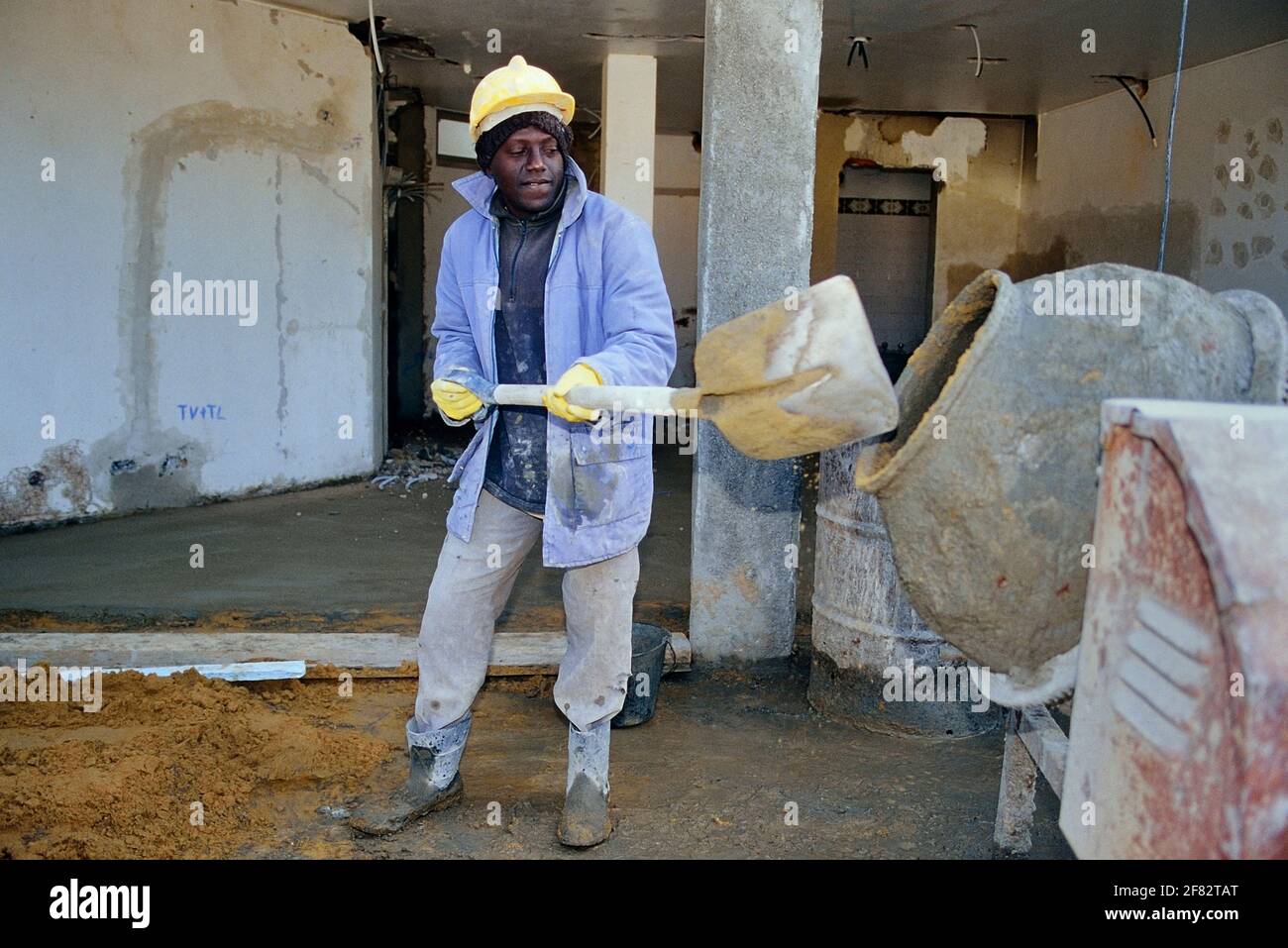 Ein schwarzer Bauarbeiter, der Zement mischt Stockfoto