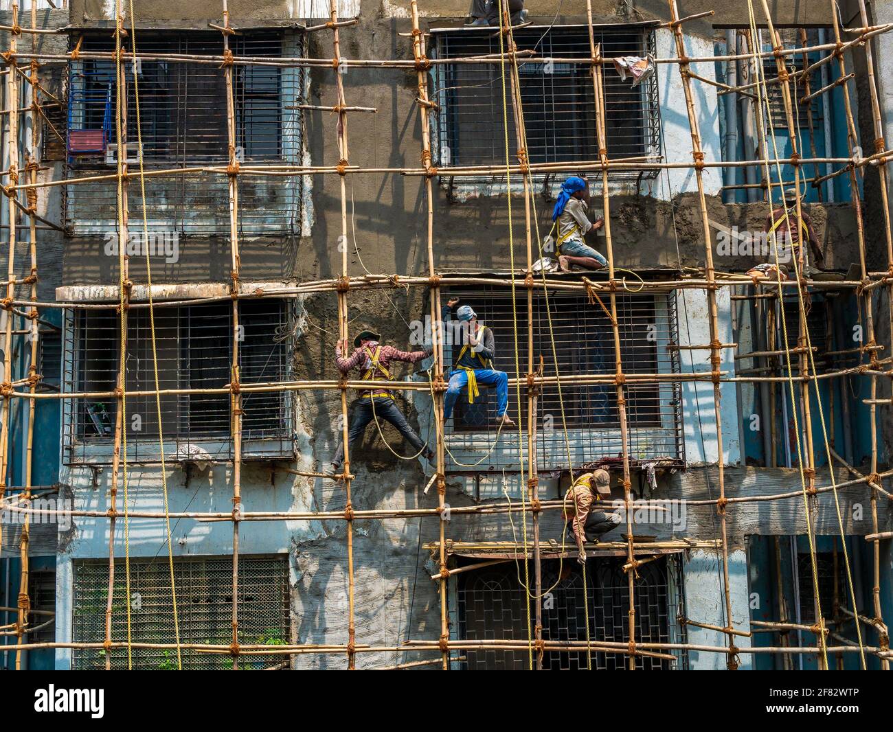 Mumbai, Indien - 20. März 2021 : Bauarbeiter bauen eine Bambusstruktur auf einer Gebäudewand, um die Instandhaltung des Gebäudes einzuleiten. Kein Schutz Stockfoto