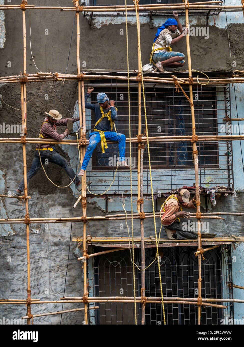 Mumbai, Indien - 20. März 2021 : Bauarbeiter bauen eine Bambusstruktur auf einer Gebäudewand, um die Instandhaltung des Gebäudes einzuleiten. Kein Schutz Stockfoto