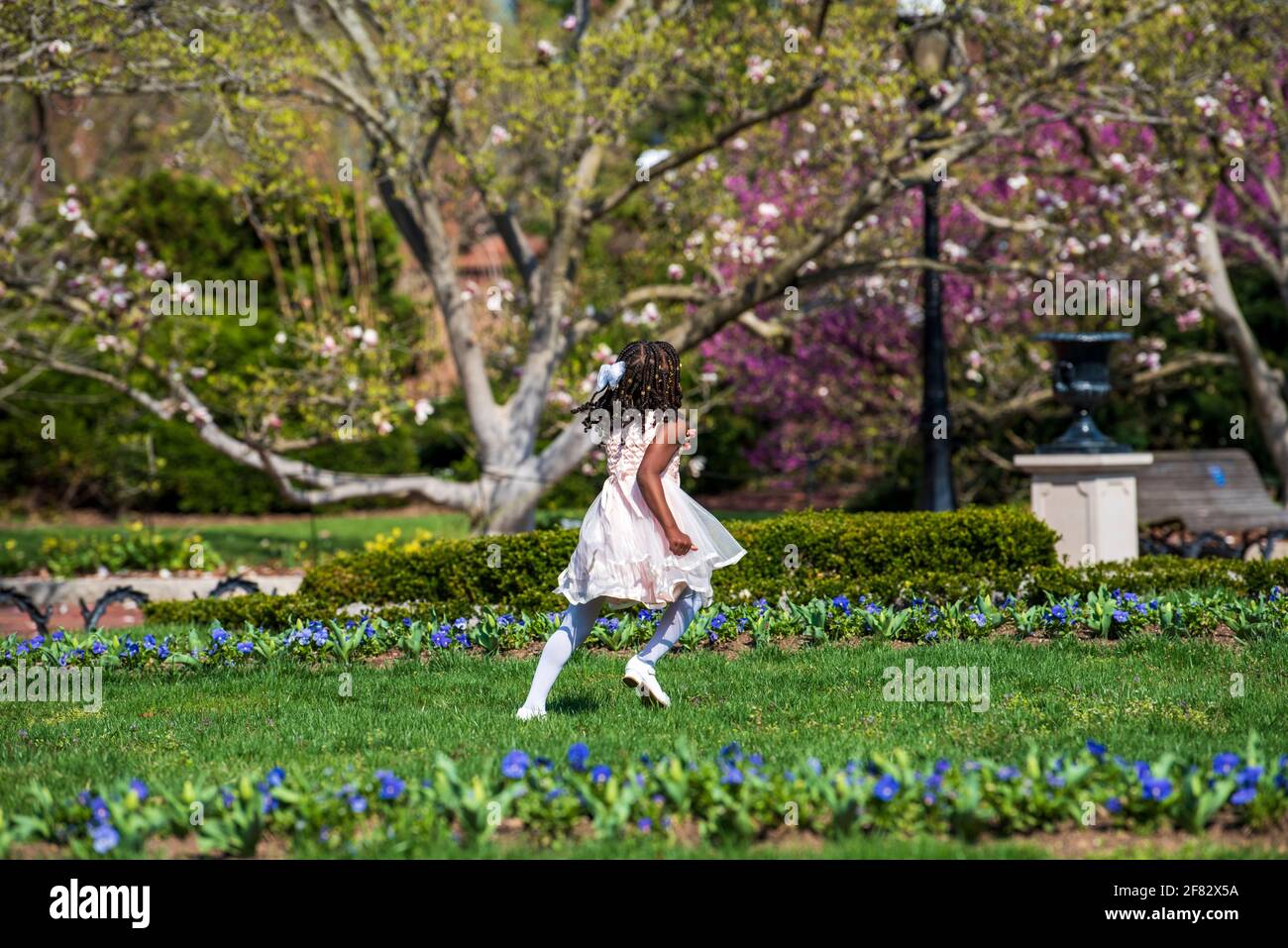 Ein junges afroamerikanisches Mädchen, das sich in ihrer Osterschönster verkleidet, durchläuft die Gärten des Smithsonian Castle in Washington, D.C. Stockfoto