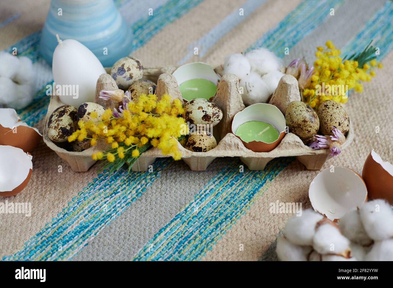 Osterdekoration in einer Eierbox mit Kerzen Eier und Getrocknete Blüten Stockfoto