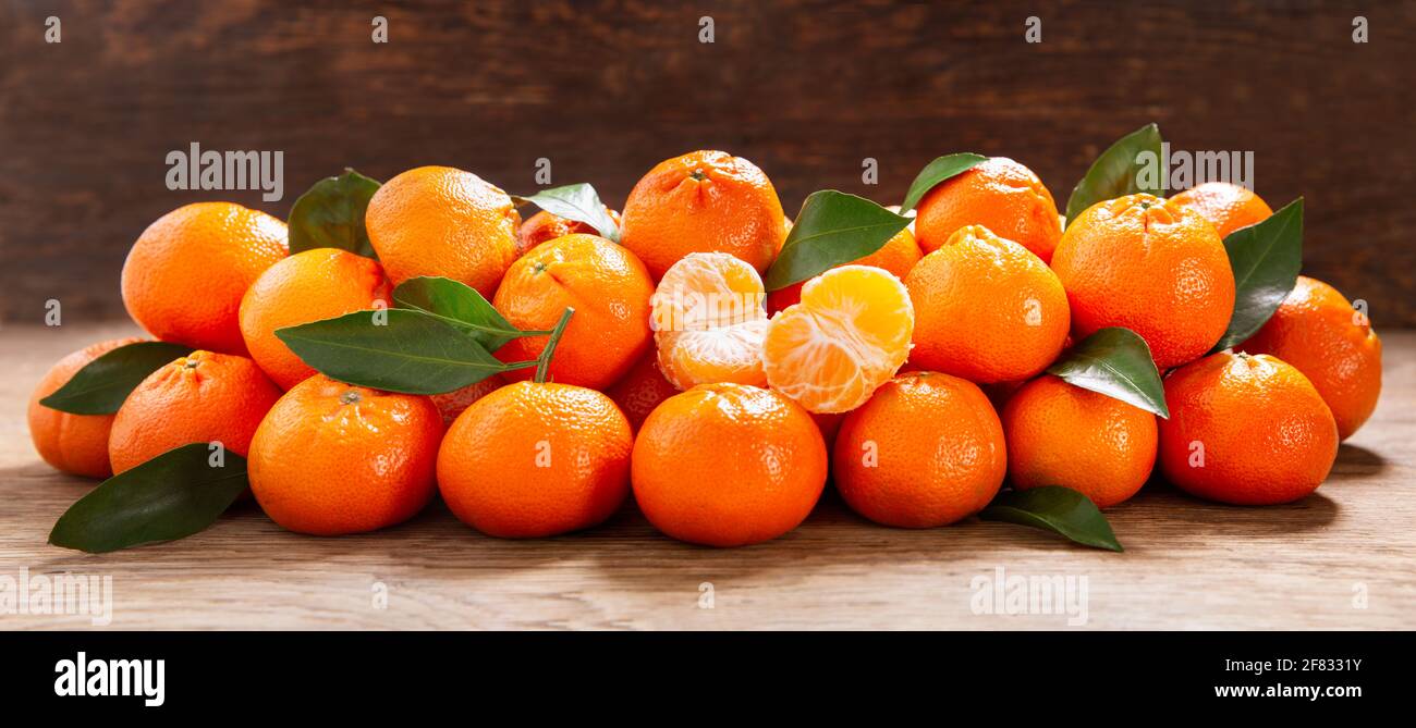 Frische Mandarinenorangen Früchte oder Mandarinen mit Blättern auf einem Holztisch Stockfoto